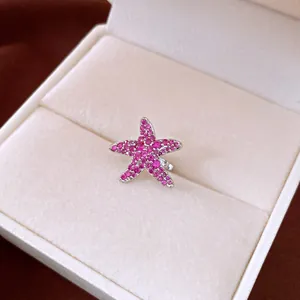 Macro detail of a sparkling pink zircon-studded starfish ear clip inside a jewelry gift box