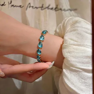 Elegant gold-tone bracelet with vibrant blue teardrop zircon stones on a wrist