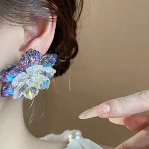 Gros plan détaillé d'une boucle d'oreille fleur en verre facetté iridescent sur une oreille