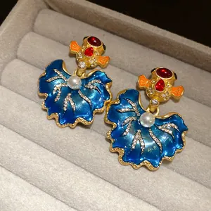 Detailed macro view of vintage gold-tone leaf earrings with blue enamel and pearls.