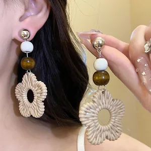 Macro view of vacation style earrings with wooden beads and resin flower pendant