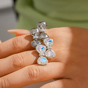 Gros plan d'une bague de luxe ornée de cristaux irisés en forme de poire sur un doigt.