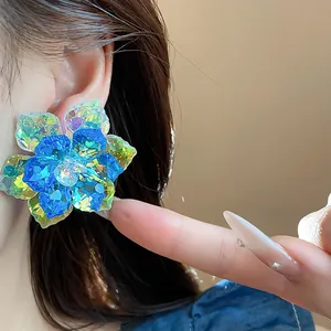 Détail en gros plan de boucles d'oreilles fleurs en verre irisées sur l'oreille d'un mannequin