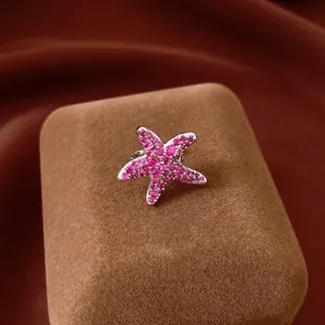 Detail view of a sparkling pink zircon starfish ear clip on a velvet jewelry box.