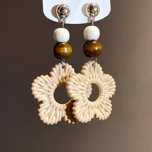 Close-up of bohemian resin flower earrings with wooden and white bead accents