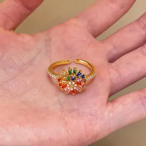 Detail shot of an 18k gold-plated floral ring with vibrant rainbow stones on a palm.