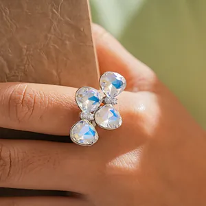 Gros plan d'une bague nœud papillon en argent avec des cristaux brillants au doigt.