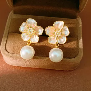 Gros plan de boucles d'oreilles fleurs roses et perles avec zircon dans un écrin