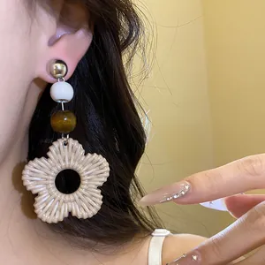 Close-up of resort style earring with wood beads and resin woven flower pendant