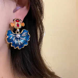 Detailed close-up of vintage blue enamel earrings featuring rhinestones and pearl accents.
