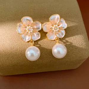 Détail de boucles d'oreilles fleurs élégantes avec zircons et pendentifs en perles