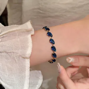 Macro view of a elegant gold chain bracelet set with faceted blue teardrop zircon stones.
