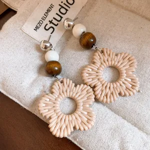 Detailed view of bohemian floral drop earrings with wooden beads and resin petals.
