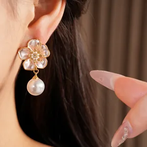Vue détaillée d'une élégante boucle d'oreille fleur avec une perle blanche pendante