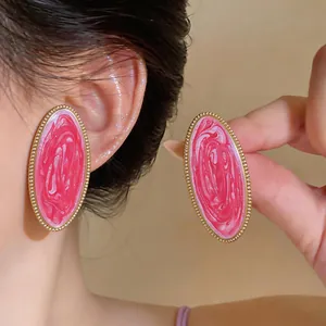 Detailansicht der übergroßen ovalen Ohrstecker mit rosa Marmorierung an einem Model