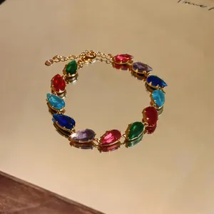 Macro detail of a gold-plated bracelet featuring colorful teardrop-shaped zircon stones