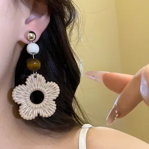 Close-up of holiday style resin flower drop earrings with wooden beads on model ear.