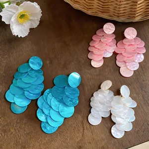 Dettaglio degli orecchini a nappa tonda in acrilico marmorizzato rosa, blu e bianco