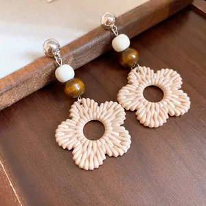 Detailed macro view of boho resin flower earrings with wooden beads on wooden base.