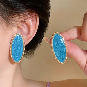 Detailansicht großer ovaler Ohrstecker mit hellblauem Emaille und Goldperlenrand.