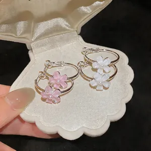 Detailed view of elegant pink and white resin flower hoop earrings in a shell box
