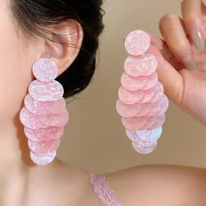 Primo piano dei pendenti a strati in acrilico rosa marmo indossati da una modella