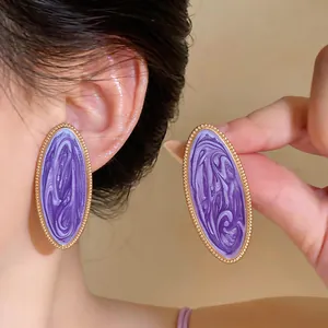 Detailansicht großer ovaler Ohrstecker mit violettem Emaille-Wirbel und goldenem Rand