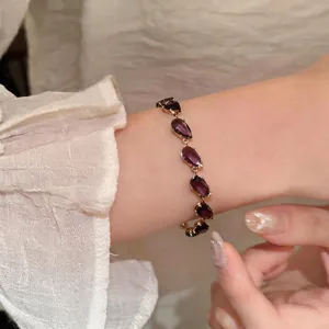 Detailed view of an elegant gold-tone bracelet featuring purple pear-cut zircon stones