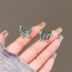 Close-up of butterfly stud earrings with iridescent shell inlay and zircon details