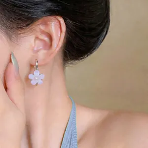 Close-up of sweet purple resin flower hoop earrings worn on ear, elegant jewelry detail.