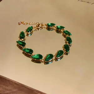 Close-up of elegant green teardrop zircon gems on a golden bracelet chain detail