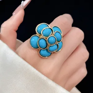 Elegant vintage style turquoise blue resin flower ring with gold textured frame on hand
