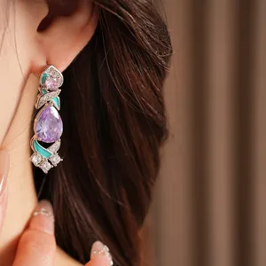 Close-up of vintage palace style drop earrings with purple zirconia and teal enamel details