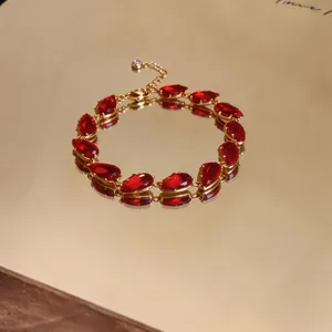 Macro view of gold-plated bracelet featuring vibrant red teardrop zircon stones on mirror