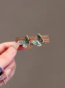 Close-up of butterfly stud earrings with colorful abalone shell and cubic zirconia