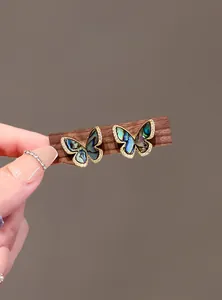 Close-up detail of vintage butterfly stud earrings featuring abalone shell and sparkling zircon