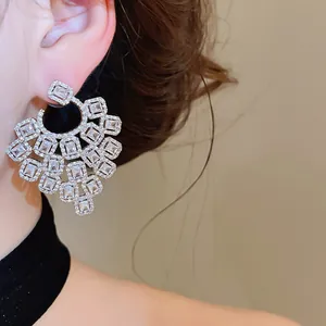 Detailed view of large ornate geometric zircon fan-shaped earrings on a model's ear