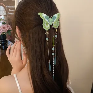 Détail d'une pince à cheveux papillon brodée verte avec de longues franges en perles