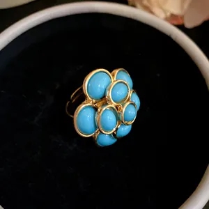 Close-up of vintage palace style flower ring with turquoise resin beads in gold tone