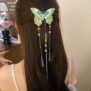 Détail d'une pince à cheveux papillon brodée verte avec d'élégants glands sur les cheveux