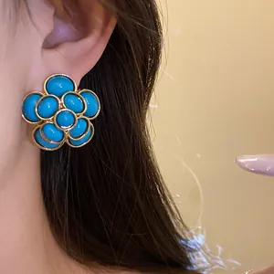Macro view of vintage gold-toned flower stud earrings with bright blue resin cabochons