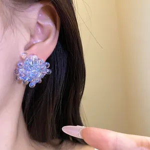 Detailed close-up showing blue cluster bead flower stud earrings worn on the ear