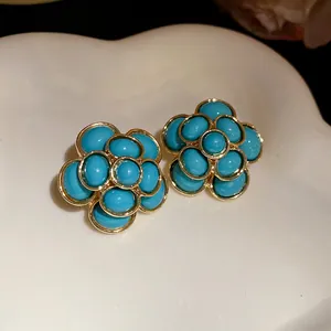 Detailed view of vintage light blue resin flower earrings with gold-toned metallic borders.