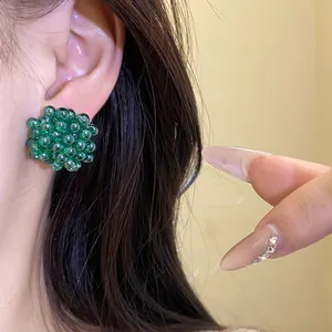 Macro detail of elegant green beaded cluster flower stud earring worn on person's ear