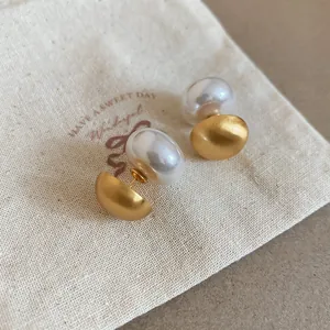 Elegant detail showing the texture of gold brushed metal and pearl two-way earrings