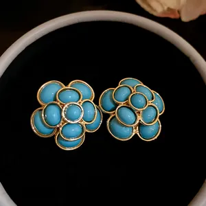 Detailed close-up of vintage-style blue resin flower earrings in a gold-toned setting