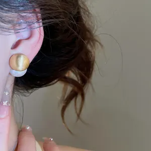 Detail shot of elegant brushed gold and white pearl two-way wear earrings on an Asian model
