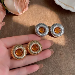 Nahaufnahme strukturierter runder Ohrstecker mit Bernsteinharz in Gold und Silber