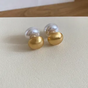 Detail view of stylish brushed gold and white pearl two-way wear stud earrings for women