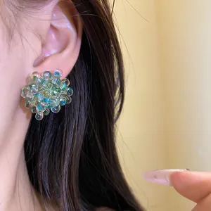 Detail view of deep blue glass bead cluster flower stud earrings on ear